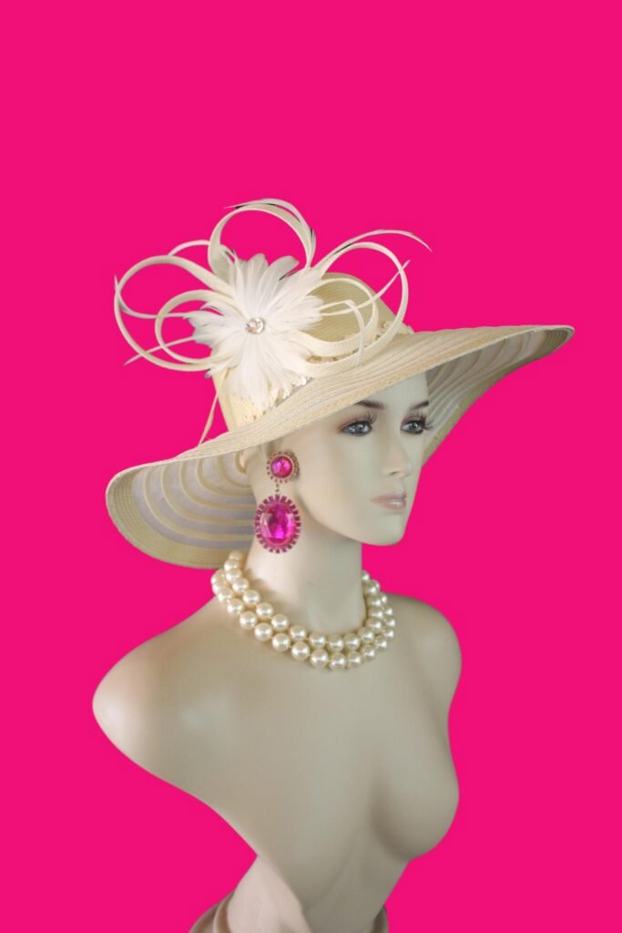 Women's Formal Couture Beige Wide Brim Designer Hat. This Custom Made Fashion Hat Is Embellished With A Handmade Natural Whitened Sinamay Straw Looped Bow White Feather Flower. A Large Acrylic Rhinestone Is Placed In The Center Of The Beautiful Feather Flower For Added Design. Delicate Goose Biot Feathers Are Placed With The Bowing. A Decorative Beige Sequin Trim Encircles The Lower Portion Of The Crown.